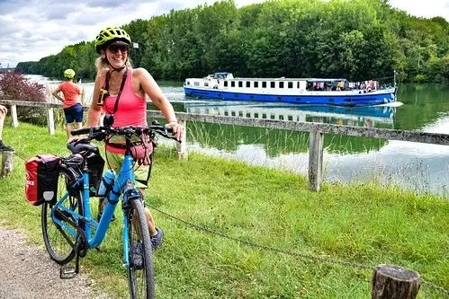 Bob Murphy with cyclists and a boat on a green riverbank
